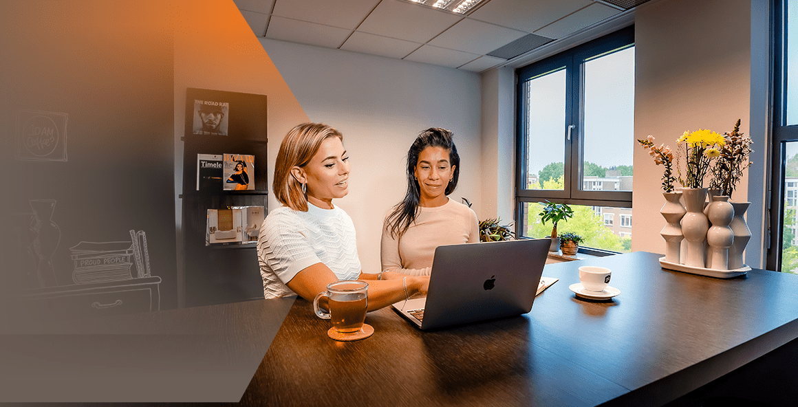 een dame wijst naar de computer de andere dame kijkt naar de computer